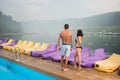 Rear view of guy with girlfriend near the luxurious resort pool enjoying perfect landscape of beautiful views