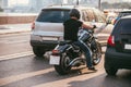 Rear view of a handsome biker dressed in a black T-shirt and black helmet jeans and sneakers. He is riding on cruiser