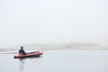 Rear view of handsome man sitting in canoe and looking in distance, guy wearing black jacket and cap, foggy autumn morning, Royalty Free Stock Photo