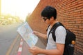 Rear view of handsome young Asian backpacker exploring the map for right direction at Chiang Mai , Thailand. Travel and tourism as