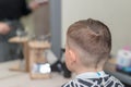 Rear view Happy Caucasian schoolboy sits in a barbershop and cuts hair