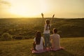 Rear view of a happy family resting looking at a beautiful sunset in the evening on nature. Royalty Free Stock Photo