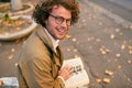 Rear view of happy handsome young man reading book outdoors. College male student carrying books in campus in autumn street. Royalty Free Stock Photo