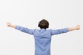 Rear view of happy student listening to music with arms raised in air over white background. Young boy student relaxing  listening Royalty Free Stock Photo