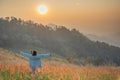 Rear view of a happy woman in the golden meadow field at sunrise time