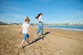 Rear view of young mother and her daughter, playing together on the beach, running and leaving footsteps on the wet sand Royalty Free Stock Photo