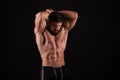Rear view of healthy muscular young man with his arms stretched out isolated on black background Royalty Free Stock Photo