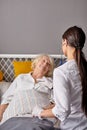 rear view on helpful female nurse checking sounds in heart and lungs of sick senior woman lying on bed