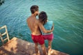 Rear view and high angle shot of couple in hug looking at beautiful blue water. Young man and woman together. Togetherness, love, Royalty Free Stock Photo
