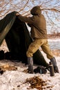 rear view on hiker setting up tent in forest, pitching in forest clearing, ready for camping Royalty Free Stock Photo