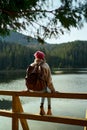 Rear view hiker woman sits on pier by beautiful mountain lake and enjoys forest landscape Royalty Free Stock Photo