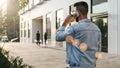 Rear view. Hipster businessman with beard, in denim jacket and trendy glasses walks around city and calls on phone Royalty Free Stock Photo