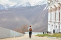 Rear view on hipster male with retro backpack walking in urban area, with beautiful landscape Royalty Free Stock Photo