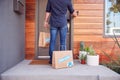 Rear View Of Home Delivery Driver Outside Front Door With Takeaway Food Bags Ringing Doorbell