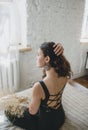 A rear view image of a beautiful amazing young brunette posing on a bed with flowers in her hands. Royalty Free Stock Photo