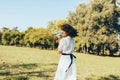 Rear view image of beautiful happy woman with windy hair enjoying the warm weather, wearing white dress on nature background. Royalty Free Stock Photo