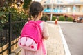 Rear view image of cute little girl preschooler walking outdoor with pink backpack against blurred buildings. Happy kid toodler Royalty Free Stock Photo