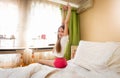 Rear view image of smiling teenage girl stretching in bed at morning Royalty Free Stock Photo