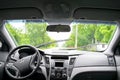 Rear view from inside mirror rain water drops falling on car window windshield glass with blurred trees nature