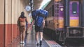 Rear view of Interracial Couple Travelers with Baggage are Walking on Platform at Chiang Mai Train Station