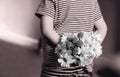 Rear view of kid with bunch of beautiful yellow Chrysanthemum behind his back in retro filter, Child in pajamas holds flowers behi