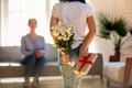 Rear view at kid daughter holding flowers and gift box