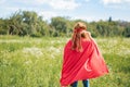 rear view of kid in red superhero cape and mask standing