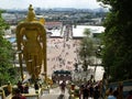 Rear view of the large golden statue of Murugan and people going down and up the stairs of the Batu Caves. Malaysia Royalty Free Stock Photo