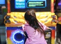 Rear view of little Asian kid girl playing arcade video game. Motorcycle Racing