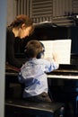 Rear view of a little boy learning piano from