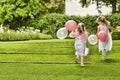 Rear view of little bridesmaids with balloons running in garden Royalty Free Stock Photo