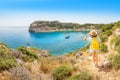 View of a lonely girl with a yellow backpack admiring a beautiful azure Bay in a tropical resort