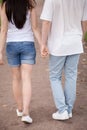 Rear view loving couple walking holding hands outdoors