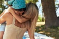 Rear view of a loving mother hugging tenderly her little daughter sitting on the blanket in the park on a sunny summer day. Woman Royalty Free Stock Photo