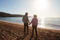 Rear View Of Loving Retired Couple Holding Hands Looking Out To Sea On Winter Beach Vacation Royalty Free Stock Photo