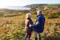 Rear View Of Loving Senior Couple Arm In Arm As They Walk Along Coast Path Royalty Free Stock Photo