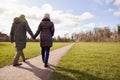 Rear View Of Loving Senior Couple Holding Hands Enjoying Autumn Or Winter Walk Through Park Together Royalty Free Stock Photo