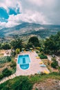 Rear view of luxury villa with swimming pool and sunbeds towards mountains and blue sky in Crete, Greece. Royalty Free Stock Photo