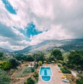 Rear view of luxury villa with swimming pool and sunbeds towards mountains and blue sky in Crete, Greece. Royalty Free Stock Photo