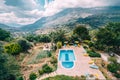 Rear view of luxury villa with swimming pool and sunbeds towards mountains and blue sky in Crete, Greece.