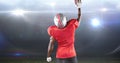 Rear view of male american football player celebrating goal by lifting ball at illuminated stadium