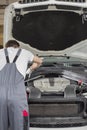 Rear view of male engineer repairing car in automobile repair shop Royalty Free Stock Photo