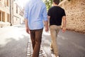 Rear View Of Male Gay Couple On Vacation Holding Hands Walking Along City Street Royalty Free Stock Photo