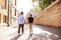 Rear View Of Male Gay Couple On Vacation Holding Hands Walking Along City Street Royalty Free Stock Photo