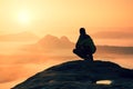 Rear view of male hiker sitting on the rocky peak while enjoying a colorful daybreak above mounrains valley Royalty Free Stock Photo