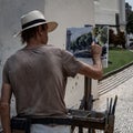 Rear view of a male street art painting on a canvas in a park