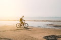 rear view of man with backpack standing and holding bike on seafront