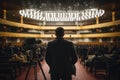 Rear view of a man with a camera in the conference hall, A cameraman with a professional digital camera stands in front of a Royalty Free Stock Photo