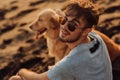 Rear view of a man and golden dog sitting on beach Royalty Free Stock Photo