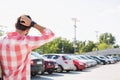 Rear view of man with hand behind head standing on city street against clear sky